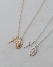 Two gold blessings necklaces with crucifix and miraculous medal pendants on a light gray background