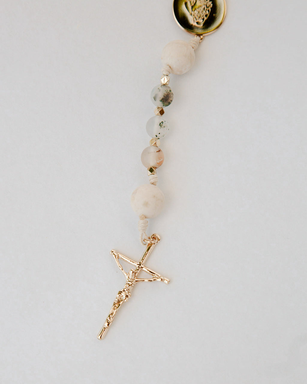 Beaded Rosary with a gold cross pendant on a light gray background