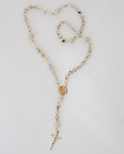 Rosary with multicolor beads and a gold cross on a light gray background