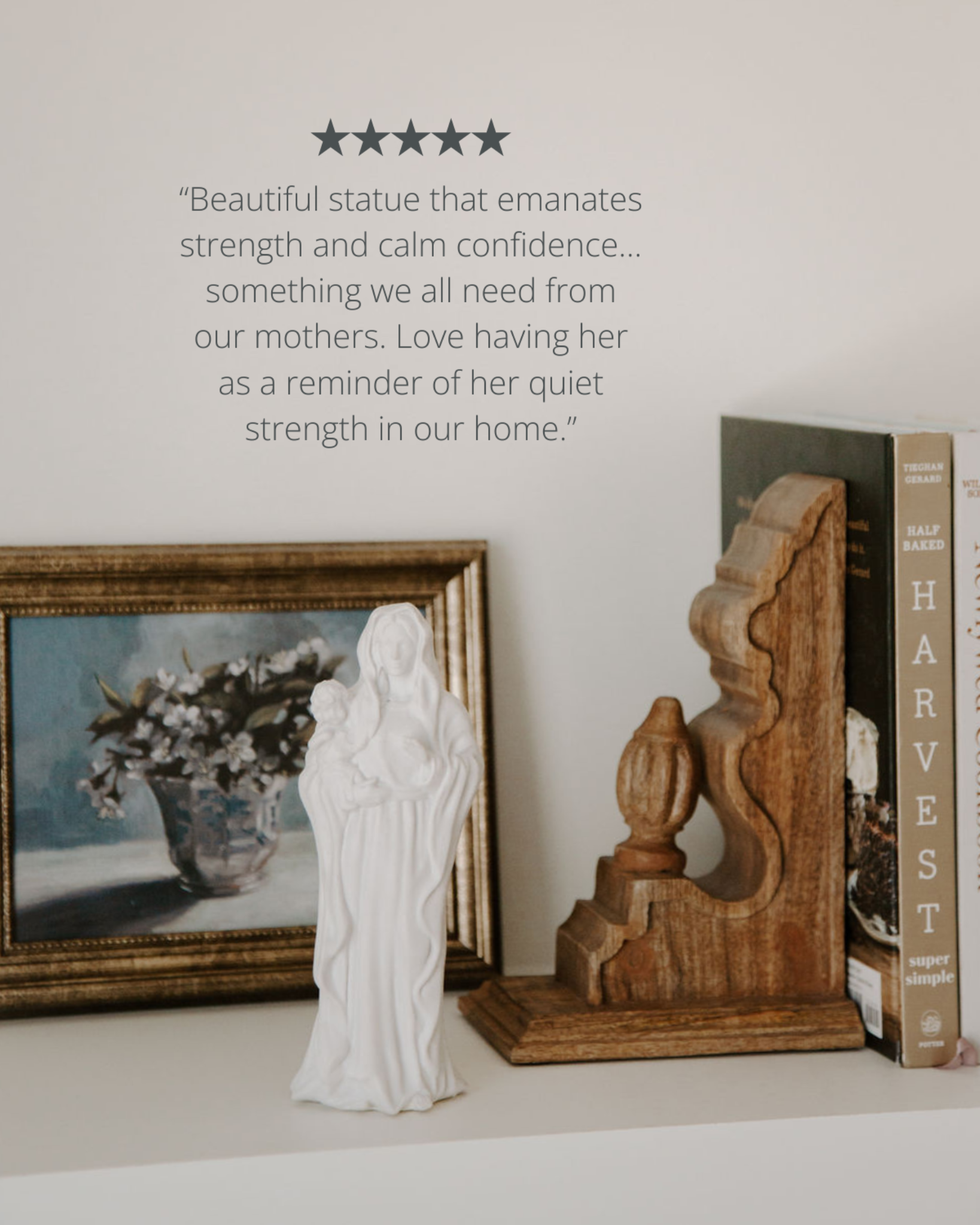 Statue of a woman holding a child on a shelf with decorative items and a book.