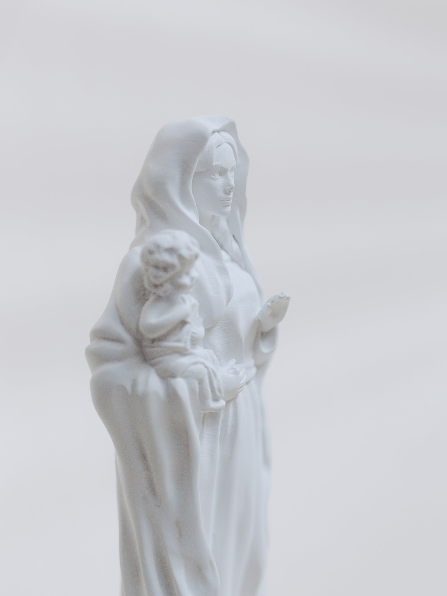 White statue of a woman holding a child against a light gray background