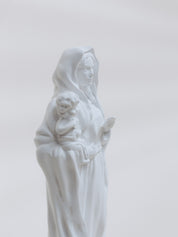 White statue of a woman holding a child against a light gray background