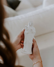 Person holding a white statue of a woman with a child against a blurred background