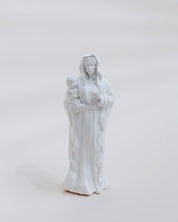 White statue of mary holding jesus on a light gray background