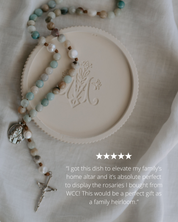 Rosary dish with engraved Marian design and rosary on a textured surface