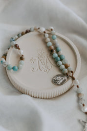 Rosary dish with gemstone rosary on fabric background