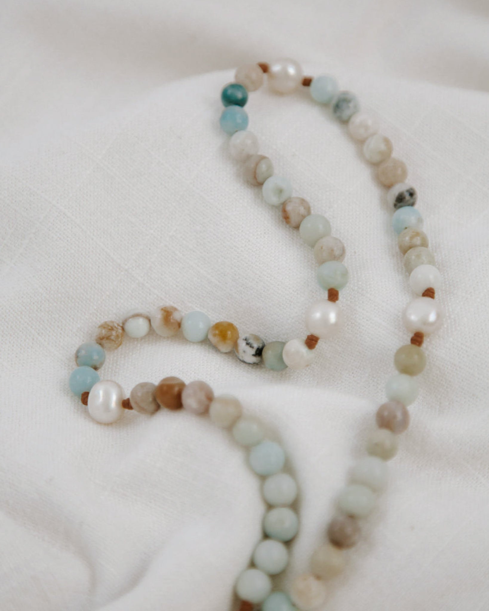 Beaded rosary with a pendant on a white fabric background