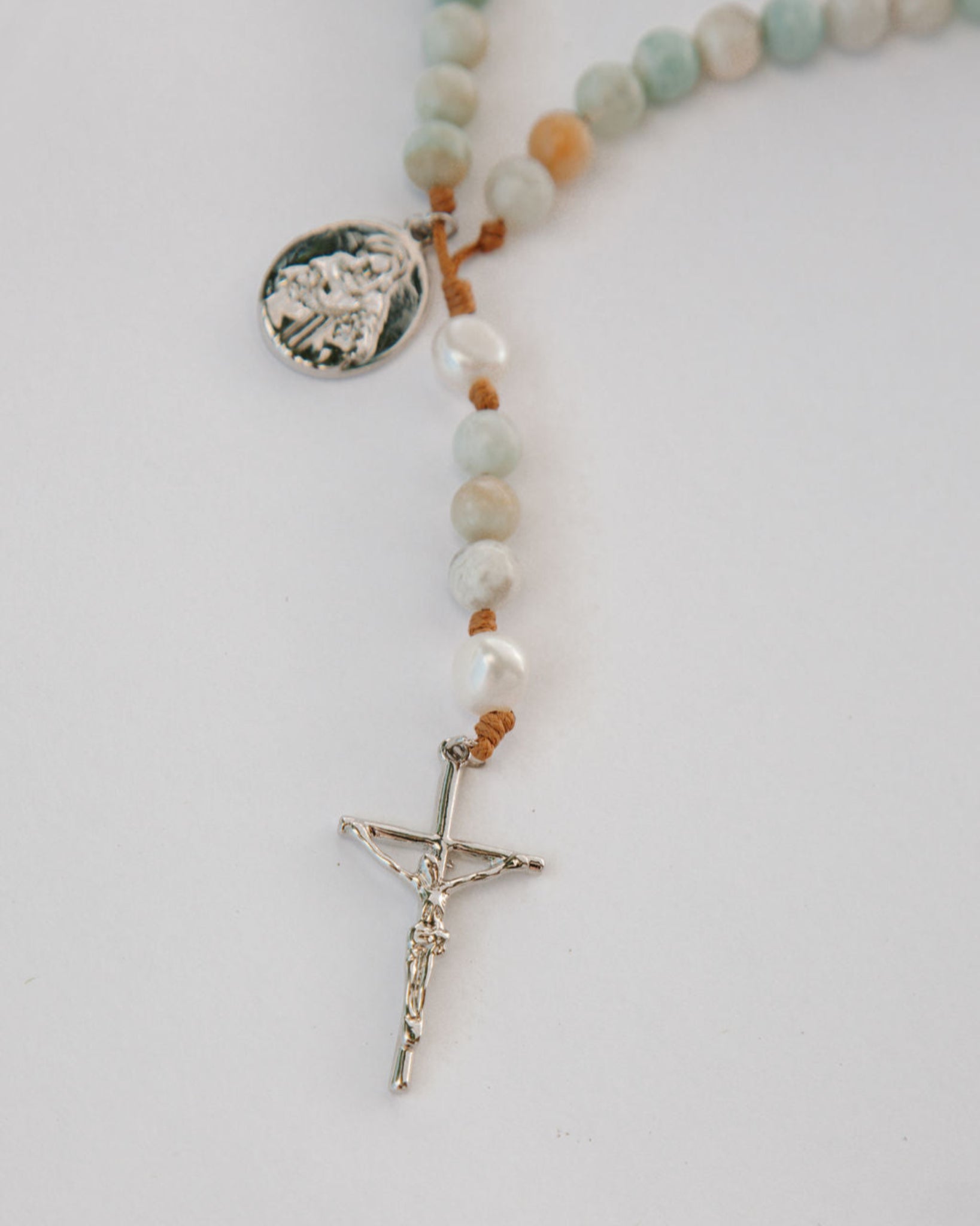Rosary with beads and cross on a light gray background