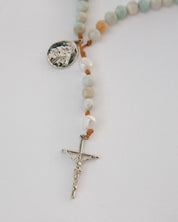 Rosary with beads and cross on a light gray background