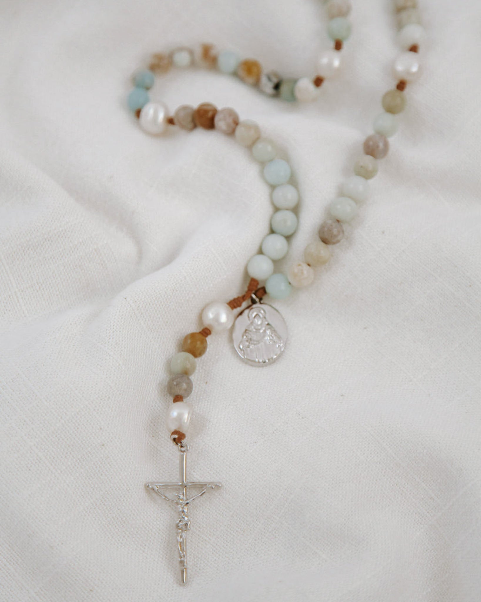 Rosary with multicolored beads and a cross on a white background