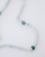 Rosary with alternating light blue and green beads on a white background