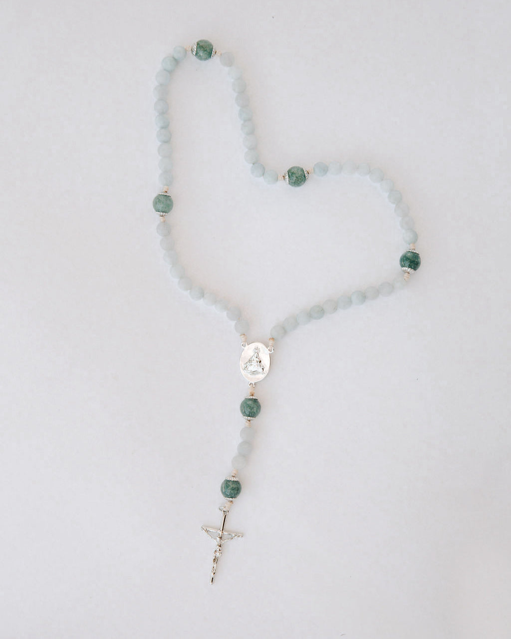 Rosary with blue and green beads on a light gray background