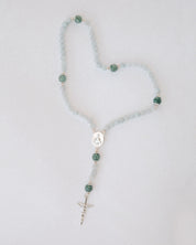 Rosary with blue and green beads on a light gray background