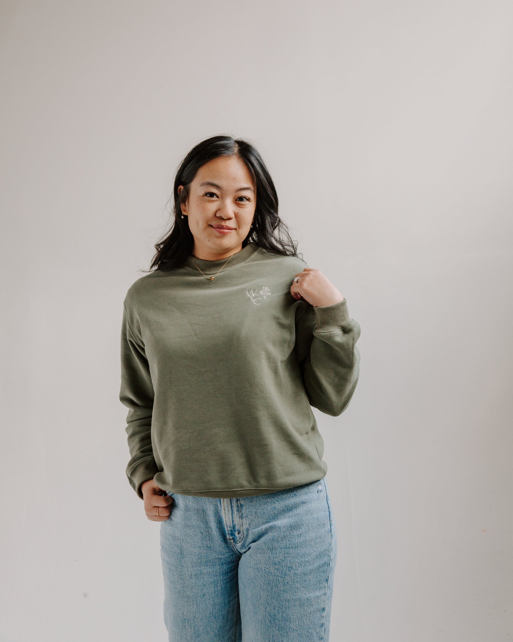 Woman wearing green crewneck with WCC logo