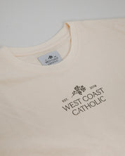 Cream tshirt with 'West Coast Catholic' text and logo on a white background