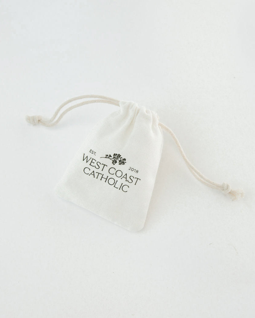 White drawstring bag with 'West Coast Catholic' text on a white background