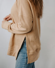 Person wearing a beige cardigan over a blue denim jacket on a plain background