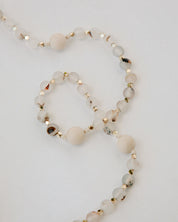 Necklace with white beads and gold accents on a light gray background