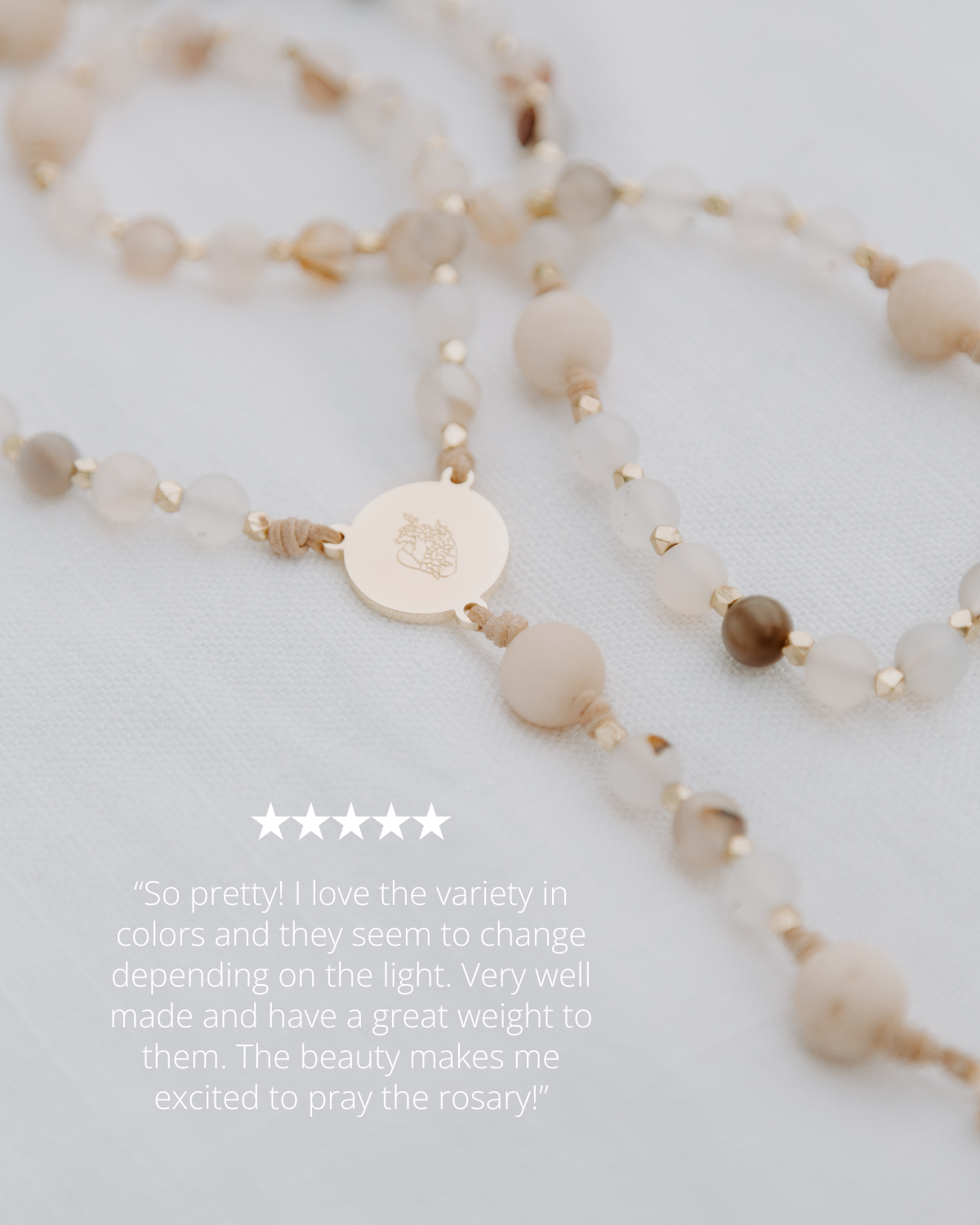 Rosary with beige beads and a gold charm on a light gray background