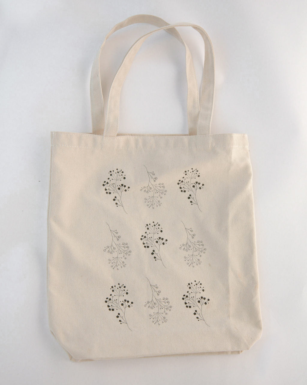 Beige tote bag with floral patterns on a light gray background