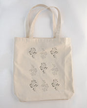 Beige tote bag with floral patterns on a light gray background