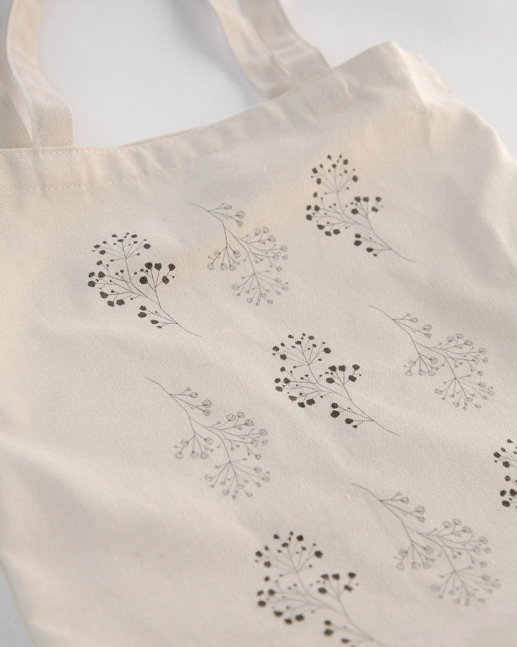 Beige tote bag with black floral patterns on a white background