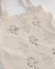 Beige tote bag with black floral patterns on a white background