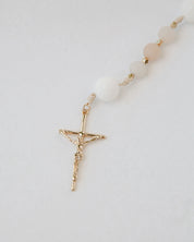 Pink and white immaculate heart rosary with gold cross on white background