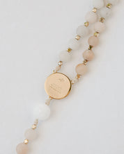 Pink and white immaculate heart rosary with gold medal on white background