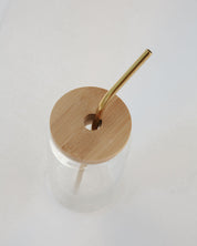 Clear glass drink container with a bamboo lid and straw on a white background