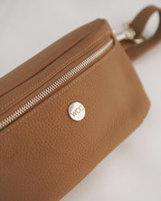 Brown leather bag with a visible brand logo on a light background