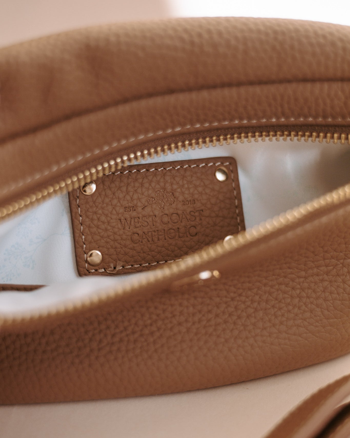 Close-up of a brown leather bag with a visible brand label on a light background