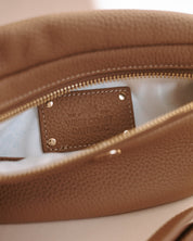 Close-up of a brown leather bag with a visible brand label on a light background