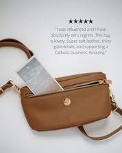 Brown leather handbag with gold accents on a light gray background