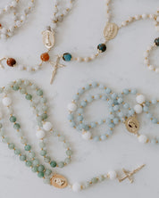 Collection of rosaries with various colored beads on a light background