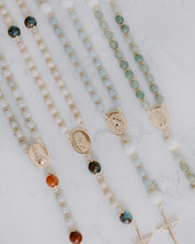 Beaded rosaries with gold medals on a marble surface