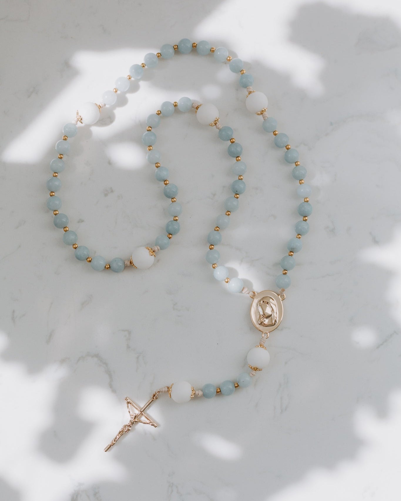 Blue gemstone rosary on a marble background