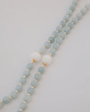 Beaded rosary with light blue beads and gold accents on a white background