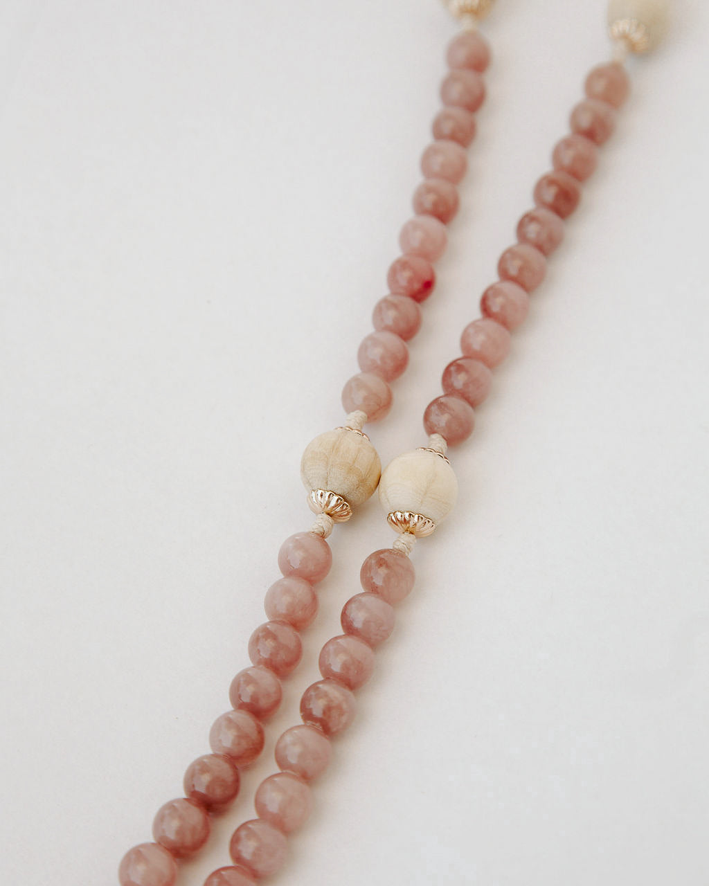 Rosary with pink and beige beads on a light background