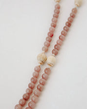Rosary with pink and beige beads on a light background