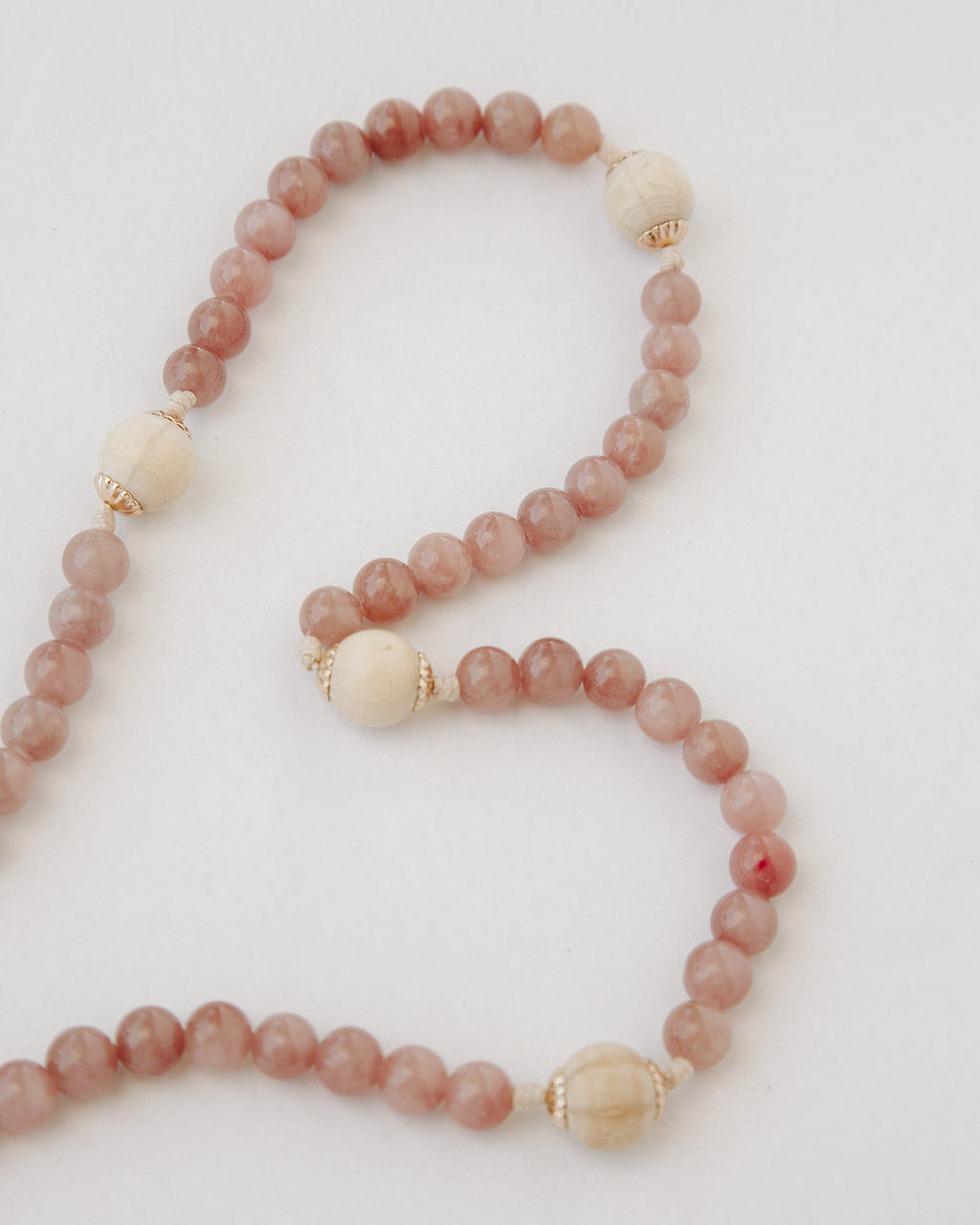 Rosary with pink and beige beads on a light background