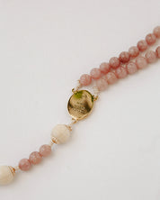 Beaded rosary with a gold medal on a light background