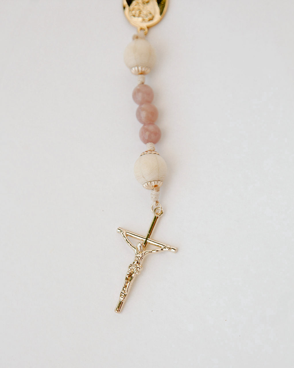 Rosary with pink beads and gold cross on a white background