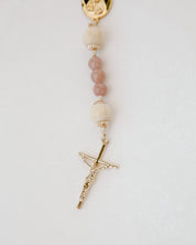 Rosary with pink beads and gold cross on a white background