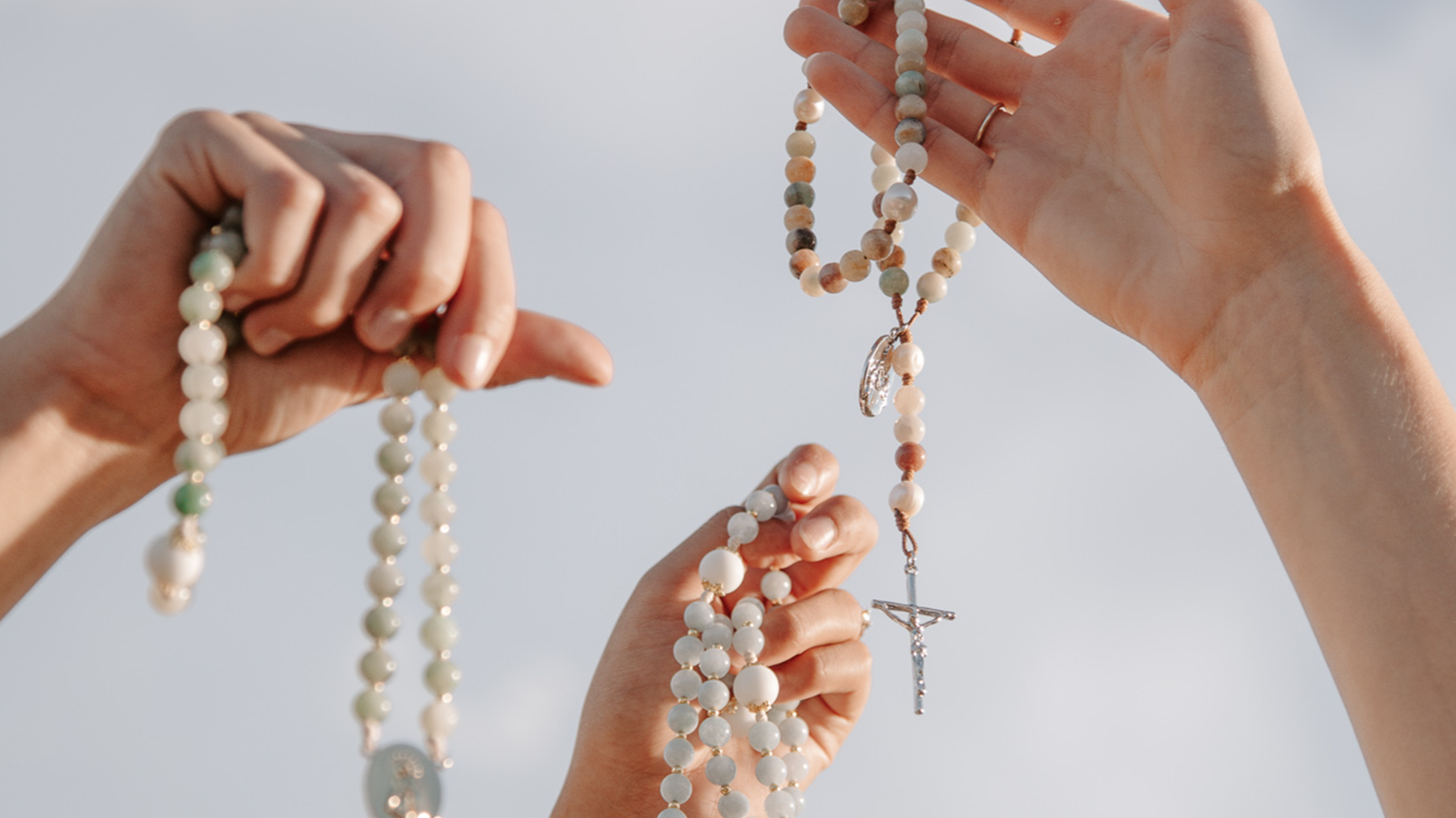 hands holding rosaries to heaven