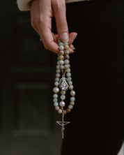 Hand holding a rosary with a blurred background