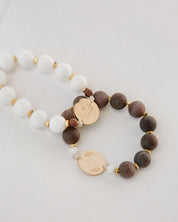 Two beaded rosaries with gold charms on a light gray background