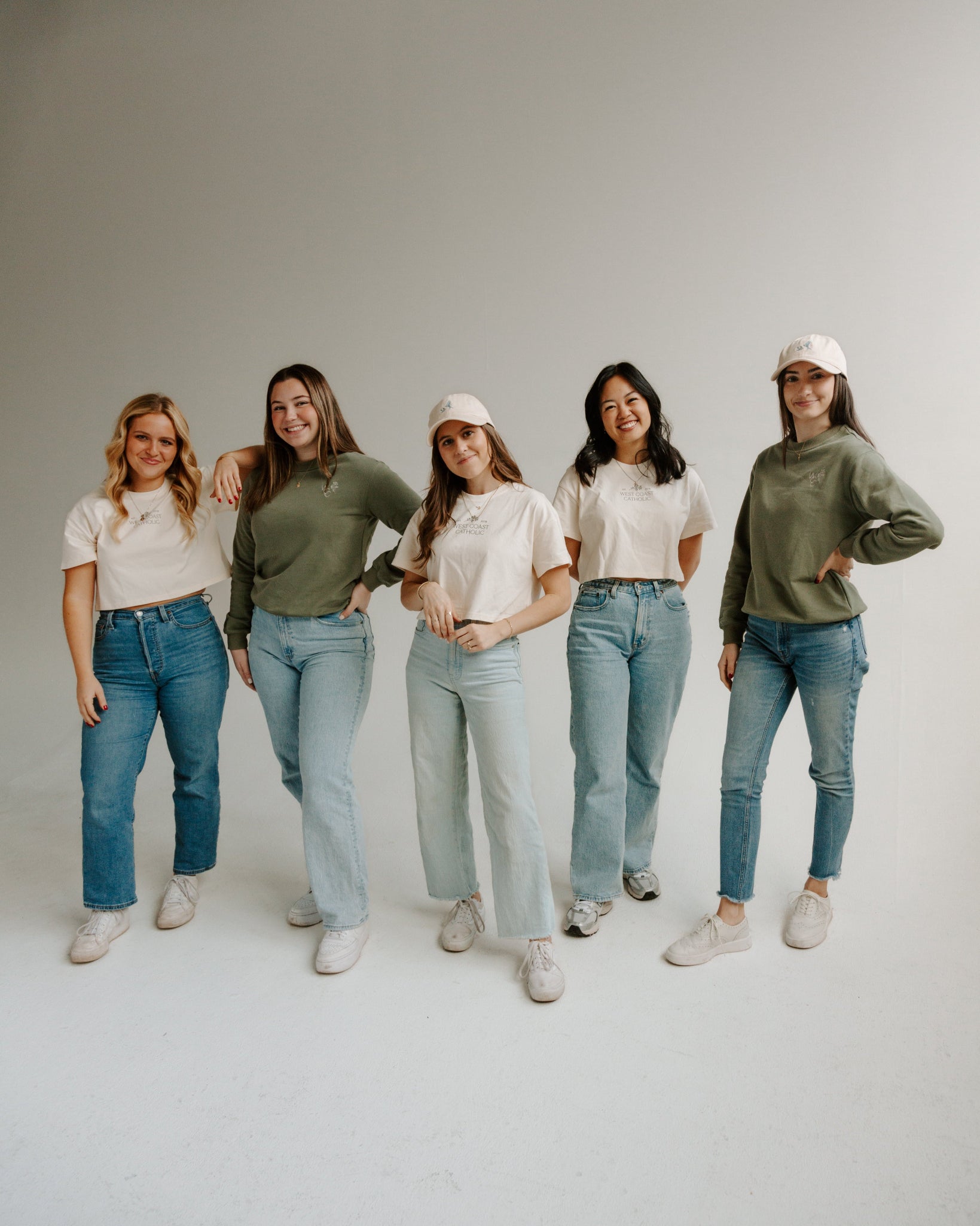 Five women standing in a line against a plain white wall.