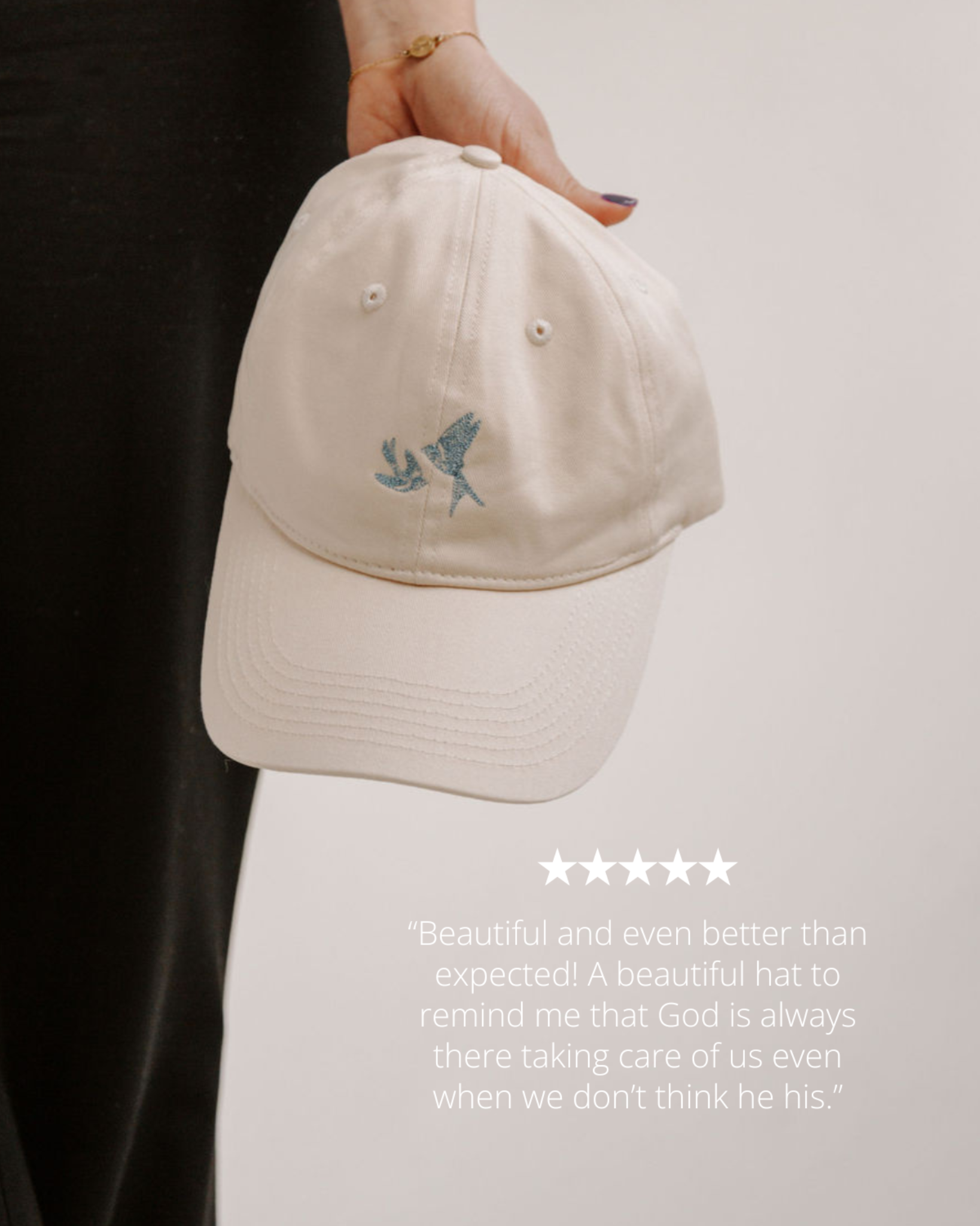 Beige cap with embroidered blue swallows held by a person, on a light background