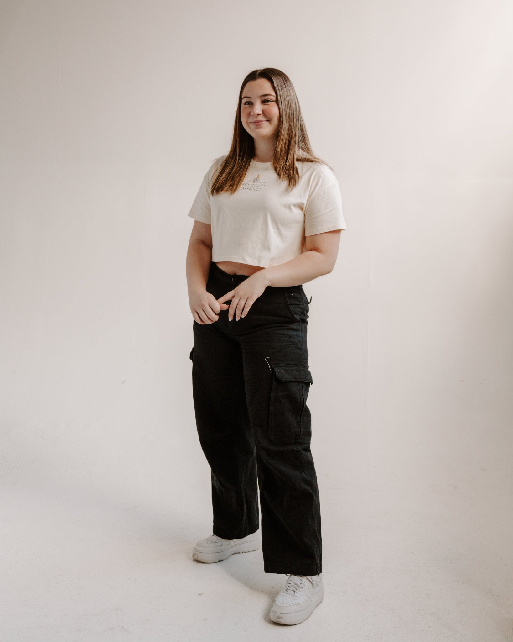 Person wearing a cream t-shirt and black pants on a plain background